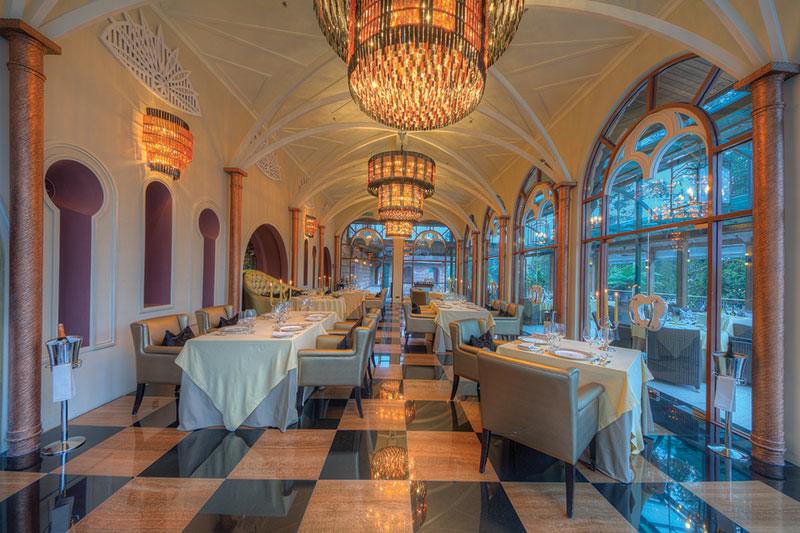A vaulted glasshouse dining hall with chandeliers